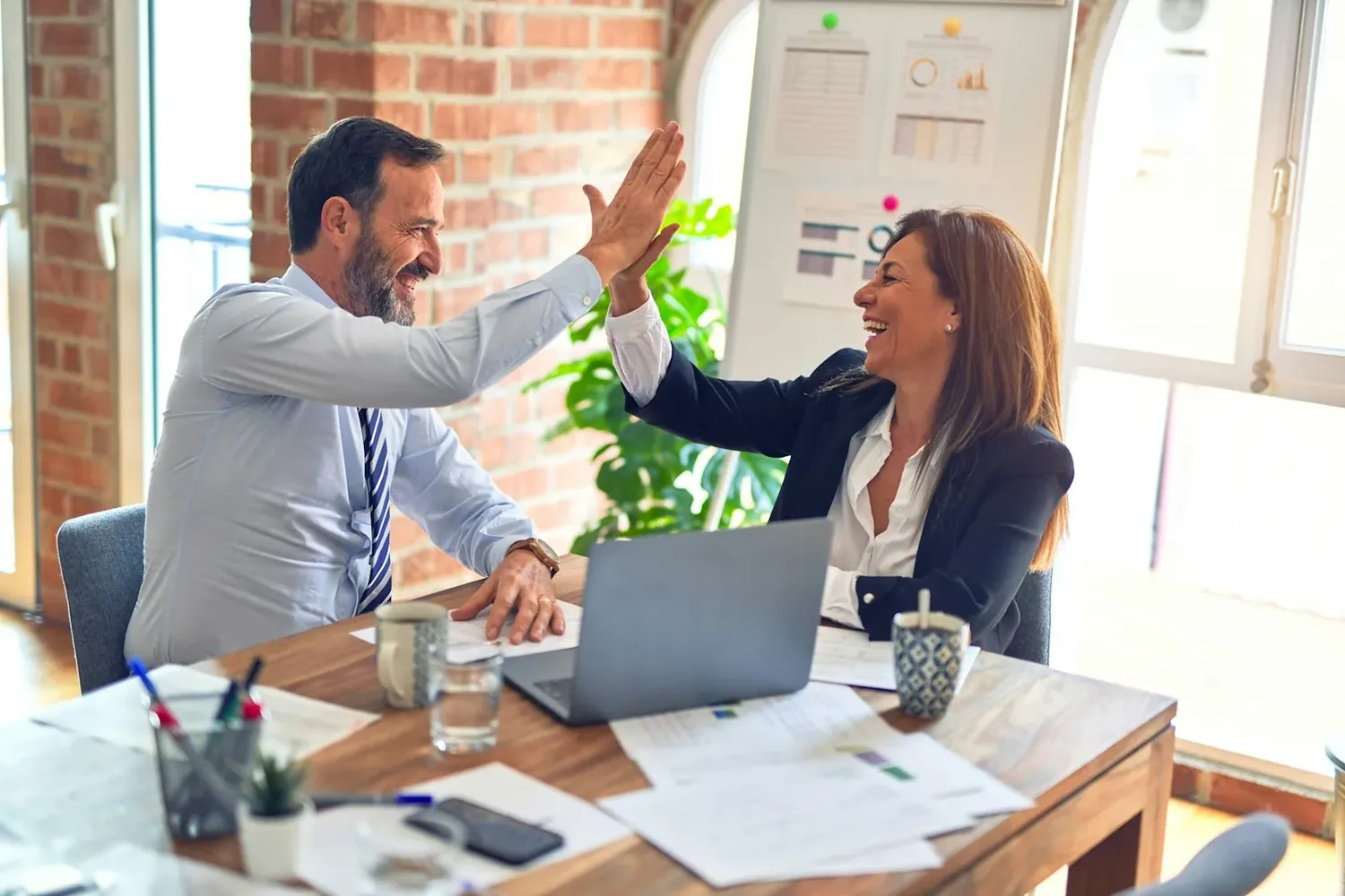 Two business partners celebrating an approval over a laptop